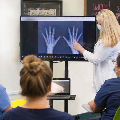 A radiography instructors showing students and x-ray of the hand